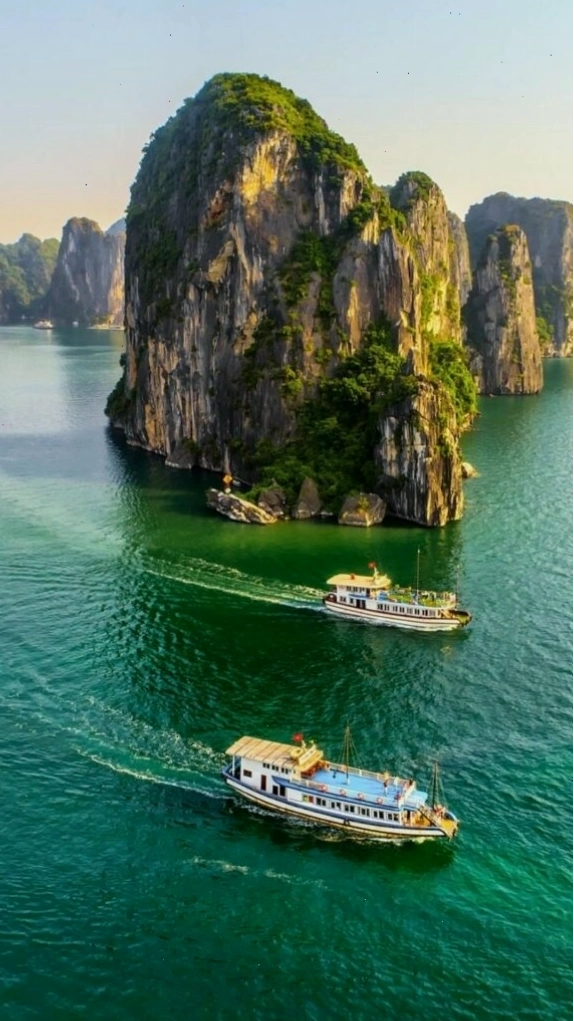 Du thuyền nhỏ giữa vịnh biển xanh và núi đá nhấp nhô